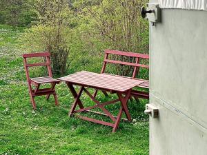 twee rode banken naast een houten picknicktafel bij 4 person holiday home in L TTORP in Löttorp