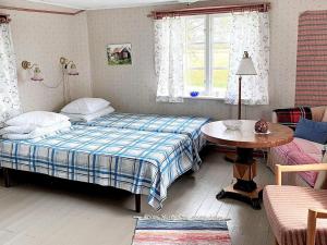 een slaapkamer met een bed, een tafel en een raam bij 4 person holiday home in L TTORP in Löttorp
