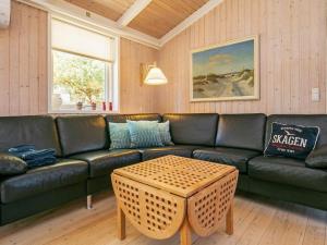 sala de estar con sofá negro y mesa en 6 person holiday home in Strandby en Strandby