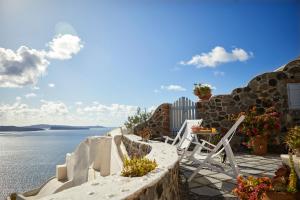 eine Terrasse mit einem Tisch, Stühlen und Wasser in der Unterkunft Lava Oia's in Oia