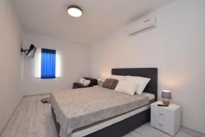 a white bedroom with a bed and a chair at Apartments Noa Nin Ždrijac in Nin