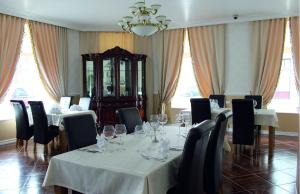 a dining room with white tables and chairs and a chandelier at Villa & Restoran Soffa in Haapsalu