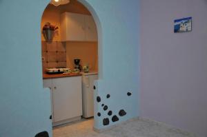 a kitchen with an archway and a white refrigerator at Studios Halaris in Perissa