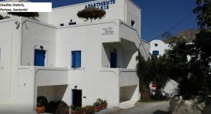 a white building with blue doors and windows at Studios Halaris in Perissa