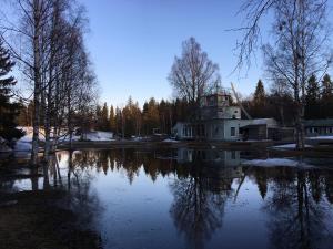 a reflection of a building in a lake with trees at Hotel Yöpuu in Kemi