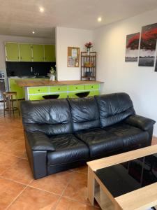 a living room with a black leather couch and a kitchen at F2 Tapu in Papeete +8 photos