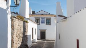 un callejón con edificios blancos y una puerta negra en Sossego da Carminho, en Monsaraz