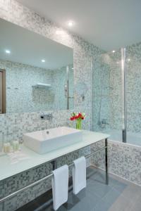 een badkamer met een bad, een wastafel en een douche bij Golden Tulip Rosa Khutor Hotel in Esto-Sadok