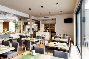a restaurant with tables and chairs and a kitchen at Hotel Martha in Beringen