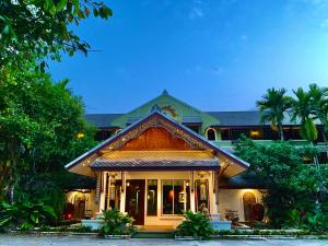 a house with a building with palm trees at Rommai Greenpark in Lampang