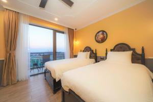 two beds in a hotel room with a balcony at Athenia Hoi An Boutique Hotel & Spa in Hoi An