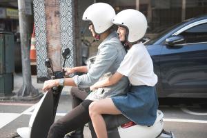 two women wearing helmets riding a scooter on the street at P&F Hotel in Taichung