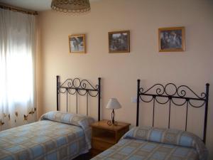 a bedroom with two beds and a lamp and a window at Casa Rural La Morena in Castroverde de Cerrato