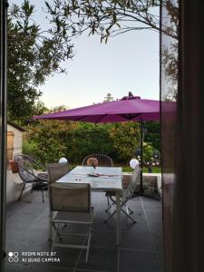 a table and chairs with a purple umbrella on a patio at Villa de charme avec piscine in Ghisonaccia
