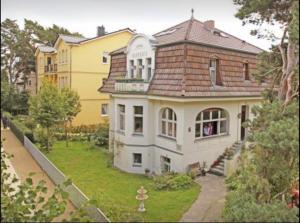 une grande maison blanche avec un toit marron dans l'établissement Villa Harmonie, à Ahlbeck