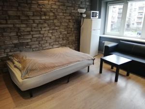 Zimmer mit einem Bett, einem Sofa und einer Ziegelwand in der Unterkunft Quiet studio apartment in the city center of Klaipeda in Klaipėda