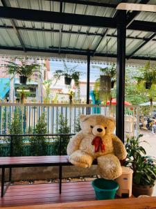 a large teddy bear sitting on a bench at Baan Mae Somkid Homestay in Sukhothai