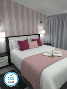 a bedroom with a large bed with pink and white pillows at Casa do Terraço in Nazaré