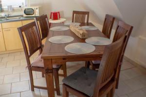 einen Holztisch mit Stühlen und Tellern darauf in der Küche in der Unterkunft Ferienwohnung Ostseefeeling 3 in Ostseebad Karlshagen