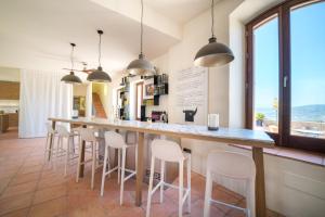 a kitchen with a long bar with white stools at Cortijo LA Organic in Ronda