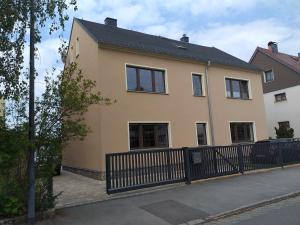 a large yellow house with a black fence at Ferienwohnung Radebeul Self Check-in in Radebeul