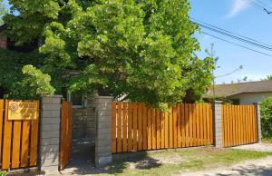 a wooden fence with a tree in front of a house at Napraforgó Vendégház in Gárdony