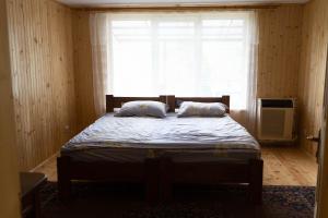 um quarto com uma cama com duas almofadas e uma janela em Садиба в пані Рузі em Skole