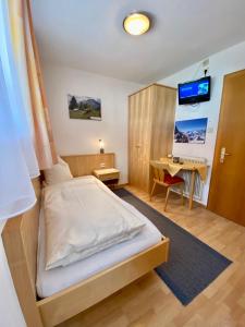 een kleine slaapkamer met een bed en een bureau bij Appartement Pension St. Sebastian in Pettneu am Arlberg