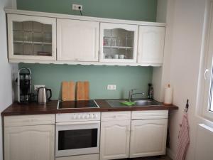 a kitchen with white cabinets and a sink at Lüttje Heide-Huus in Soltau