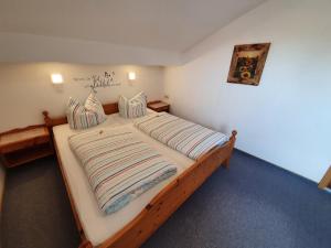 a bedroom with a large wooden bed with striped pillows at Haus Bayrhof in Hopferau +25 photos
