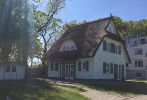 Cette grande maison blanche est dotée d'un toit de chaume. dans l'établissement Traditionelles Reethaus direkt an der Ostsee, à Rerik