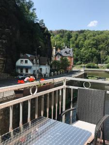 uma mesa e cadeiras numa varanda com vista para um rio em Hotel Kotva em Hřensko