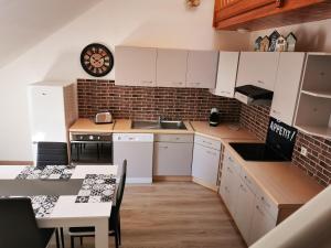 Una cocina con gabinetes blancos y un reloj en la pared. en L'Ancre Marine, en Cancale 14 fotos más