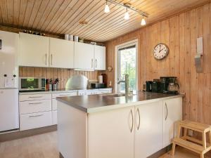 una cocina con armarios blancos y un reloj en la pared en 8 person holiday home in Tranek r, en Tranekær