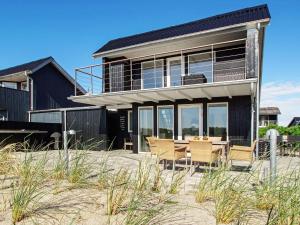 a house on the beach with a table and chairs at 6 person holiday home in Hemmet in Hemmet