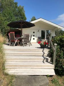 una terraza de madera con 2 sillas y una sombrilla en Lyckhus, en Ljungskile