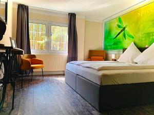 a hotel room with a bed and a desk and windows at Spree - Waldhotel Cottbus in Cottbus +26 photos