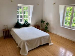 a bedroom with a white bed and two windows at Villa Erbschloe in Remscheid