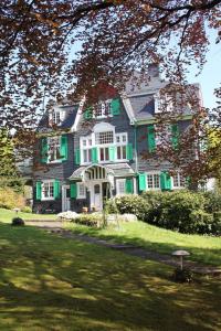 a large house with green shutters on a lawn at Villa Erbschloe in Remscheid