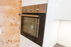 a black oven in a kitchen next to a wooden wall at Haus Miranda Grächen in Grächen