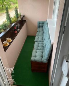 a living room with a blue couch and a green floor at VESTA Apartman in Sremska Mitrovica