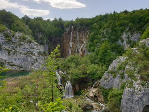 a waterfall in the middle of a mountain with trees at Plitvice Diamond Apartment in Korenica