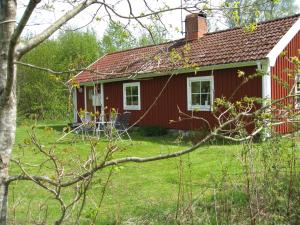 una casa roja con un patio verde delante de ella en Tildas Urshult en Urshult