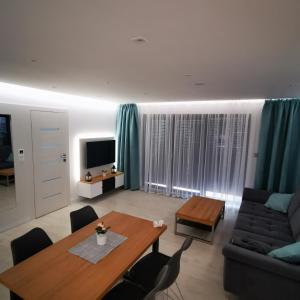 ein Wohnzimmer mit einem Tisch und einem Sofa in der Unterkunft Apartament IDEAL in Dziwnów