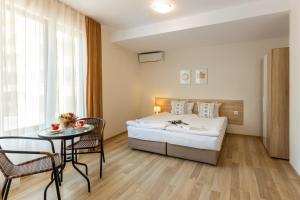 um quarto de hotel com uma cama, uma mesa e cadeiras em Apartments Flora 1 em Burgas