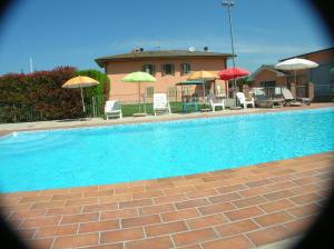 a swimming pool with chairs and umbrellas in front of a house at VILLA MARIA in Altopascio