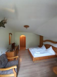 um quarto com uma cama e uma cadeira num quarto em Gasthof Und Hotel Maria Gern em Berchtesgaden