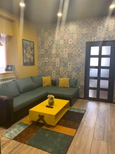 un salon avec un canapé bleu et une table jaune dans l'établissement Trakia Street Apartment, à Plovdiv