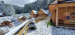 un groupe de cabines en bois avec de la neige au sol dans l'établissement Cicha Polana, à Szczyrk