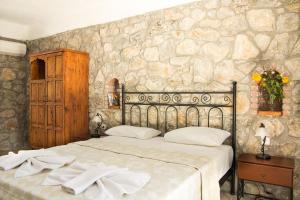 a bedroom with a bed and a stone wall at Doga Apartments in Kayakoy